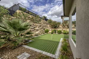 Fenced backyard featuring a putting area and a patio area