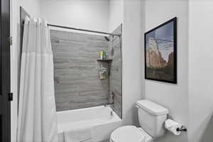 Bathroom featuring toilet and shower / bath combination with curtain