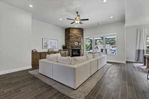 Living area with wood finish floors, ceiling fan, recessed lighting, and a stone fireplace