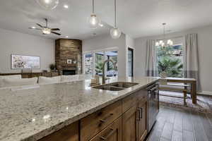 Kitchen with wood tiled floors, a fireplace, wood finish cabinetry, a chandelier, and a ceiling fan