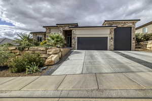 Prairie-style house featuring an attached garage, stone siding, stucco siding, and driveway