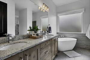 Full bath with tile walls, double vanity, a freestanding tub, light tile patterned floors, and a stall shower
