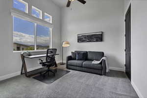 Carpeted office space featuring a high ceiling and ceiling fan