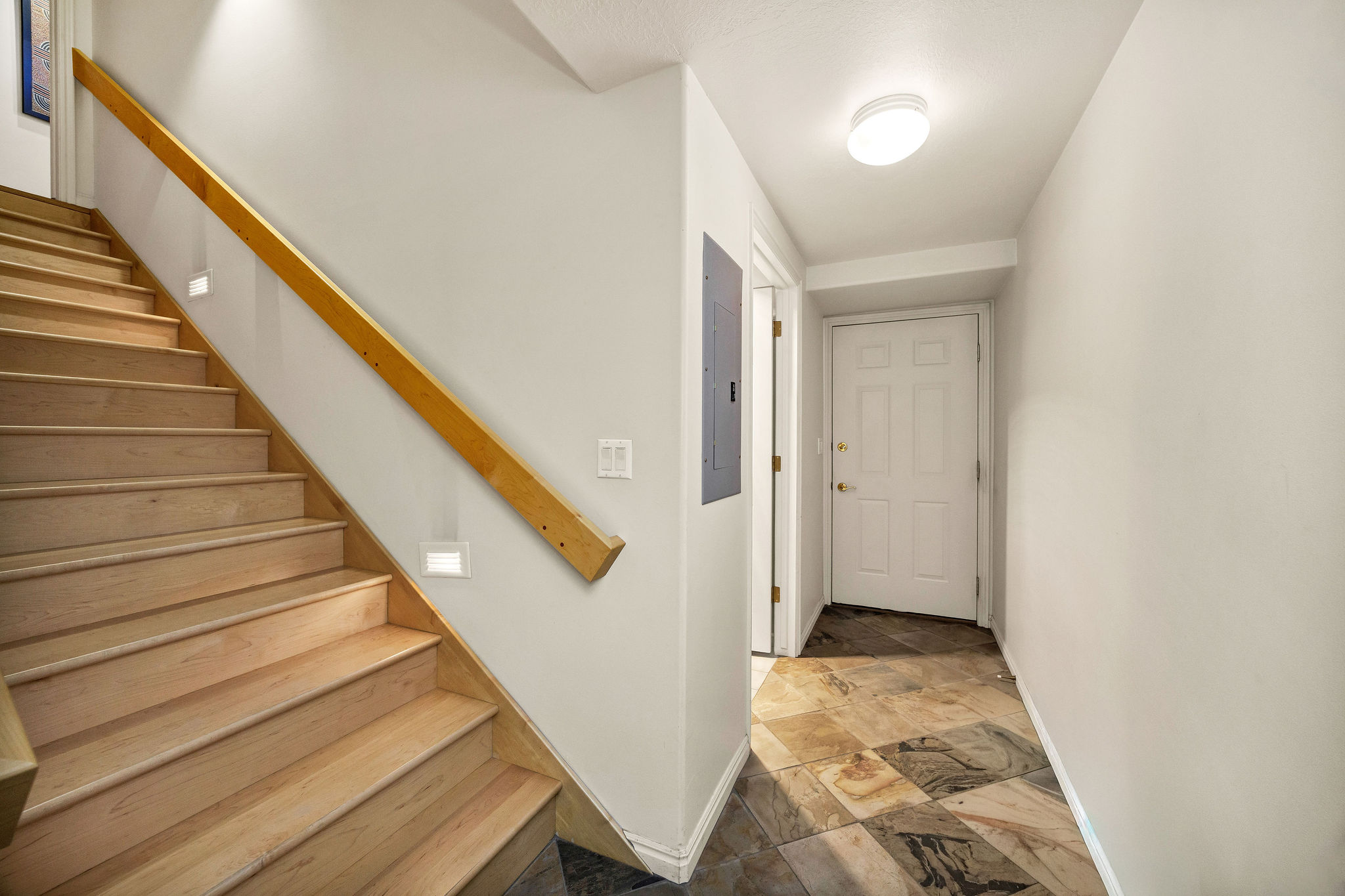 Stairs featuring electric panel and stone finish floors in from the 3 car garage