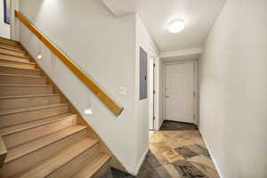 Stairs featuring electric panel and stone finish floors in from the 3 car garage