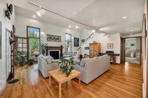 Living room featuring rail lighting, light wood-style flooring, and a glass covered fireplace