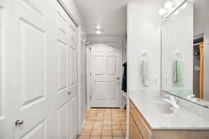 Bathroom with vanity, light tile patterned floors, and a closet