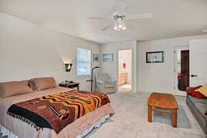 Bedroom featuring light carpet, a ceiling fan, and ensuite bath