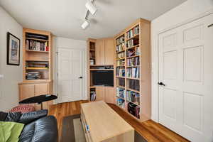featuring light wood-type flooring and track lighting Built in Cabinets and Shelves.