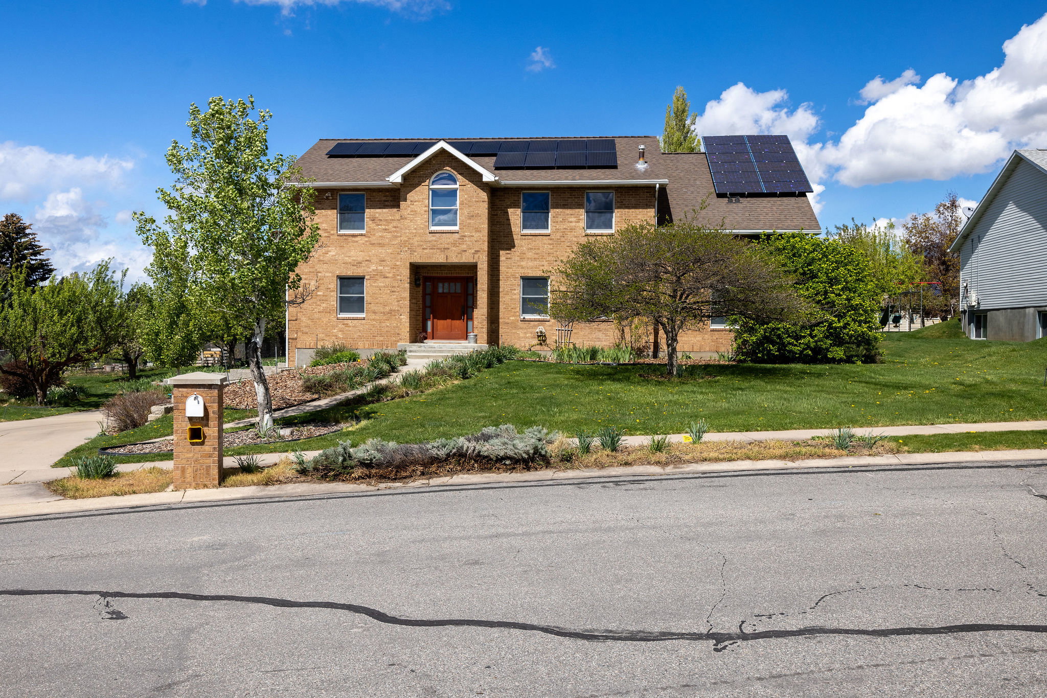 View of front of property with a front yard, solar panels, and brick siding