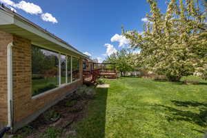 View of green lawn featuring a wooden deck