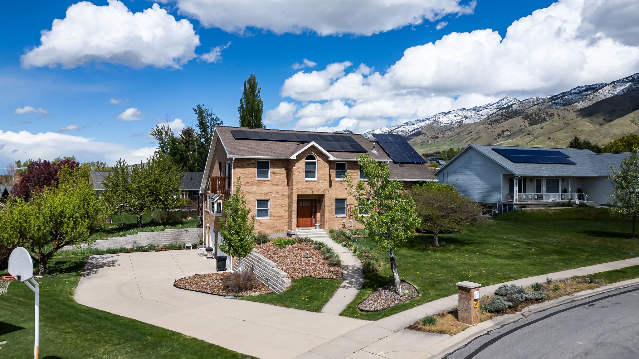 View of front of property featuring a front lawn, roof mounted solar panels, a mountain view, concrete driveway, and brick siding