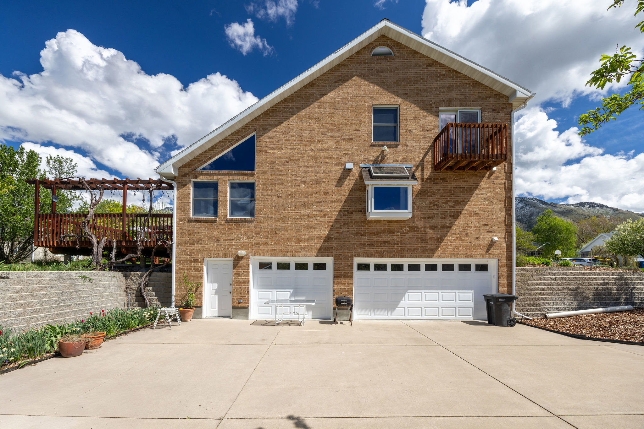 View of home's exterior featuring a garage, brick siding, a patio area, a pergola, and concrete driveway