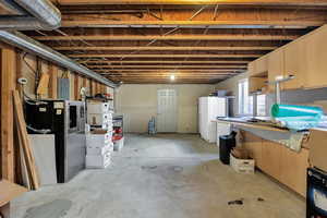Basement family room framed and featuring freestanding refrigerator, electric backup battery, and refrigerator