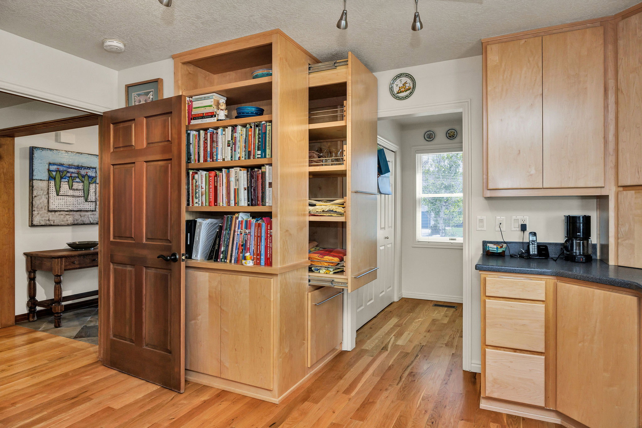 Kitchen featuring light wood finish cabinets, a textured ceiling, light wood-style floors, and dark Corian countertops