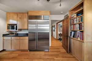 Kitchen featuring stainless steel appliances, a textured ceiling, light wood finished floors, and light wood finish cabinetry