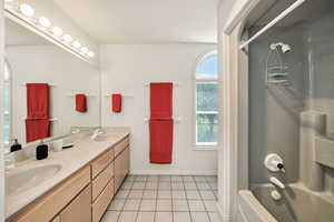 Full bath with double vanity, shower / bathtub combination, and light tile patterned flooring