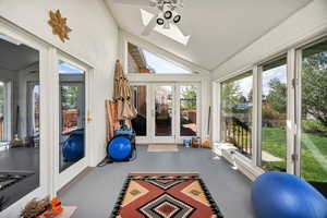 Workout room featuring a skylight, finished concrete flooring, a ceiling fan, and lofted ceiling