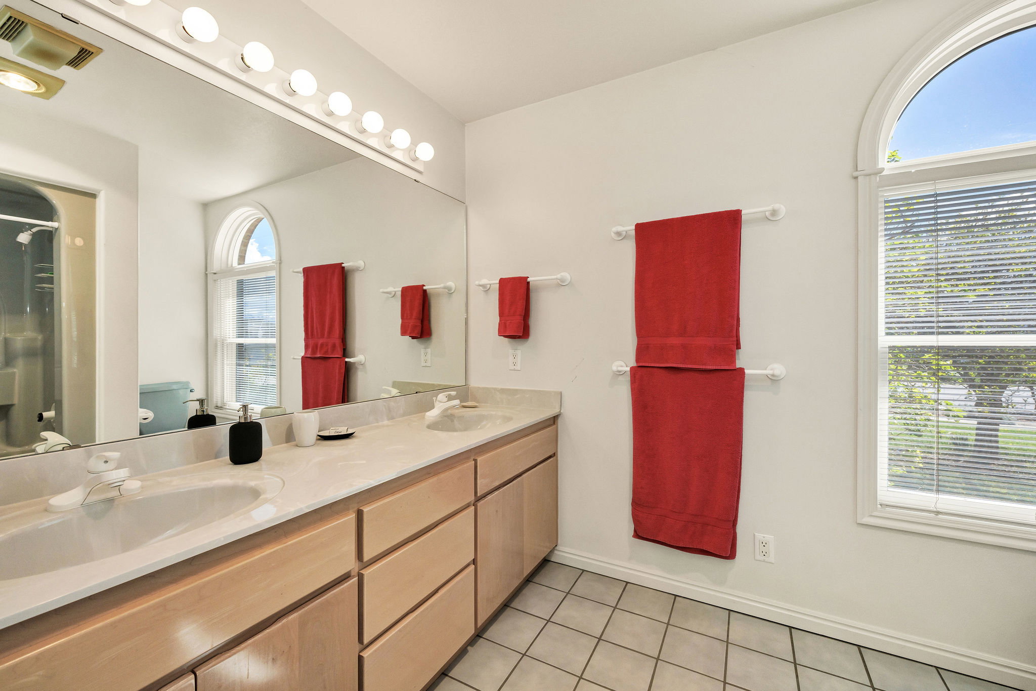Full bath with double vanity, light tile patterned flooring, and a shower