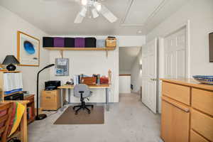 Office/ bedroom space with a ceiling fan, light colored carpet, and door to full bathroom