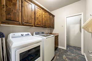 Laundry room with stone finish floors, washer and clothes dryer, and cabinet space
