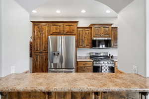 Kitchen with stainless steel appliances, arched walkways, recessed lighting, wood finish cabinetry, and a peninsula