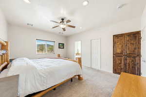 Carpeted bedroom with a ceiling fan, ensuite bath, and recessed lighting