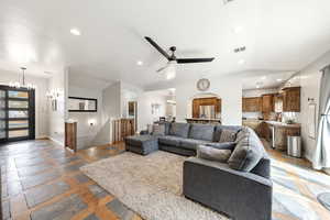 Living area featuring hanging lights, stone tile floors, arched walkways, and ceiling fan
