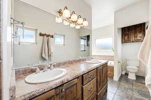 Bathroom with double vanity and dark stone finish floors