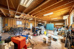 Misc room with a garage, a workshop area, and unfinished concrete floors