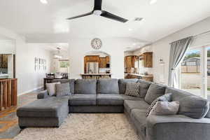 Living area featuring ceiling fan, stone tile flooring, recessed lighting, and vaulted ceiling