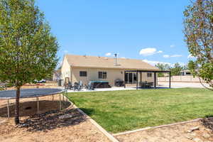 Rear view of property with a patio area, stucco siding, a fenced backyard, and a trampoline
