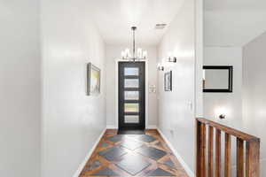 Entrance foyer featuring a chandelier and inlaid floor details
