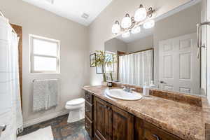 Full bathroom featuring vanity, dark stone finish floors, and a shower with shower curtain