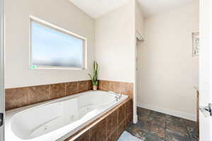 Bathroom with stone tile floors and a tub with jets