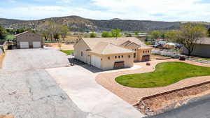 View of front facade featuring stucco siding, driveway, a mountain view, and a front yard