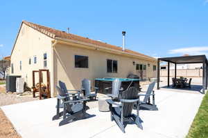 Back of property with a patio area, outdoor dining space, stucco siding, a hot tub, and a gazebo