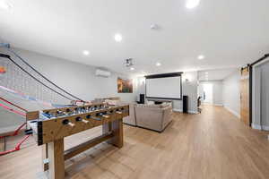 Game room featuring a barn door, light wood-style floors, and recessed lighting