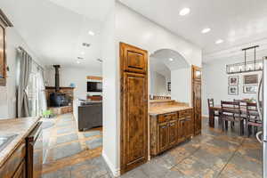 Kitchen featuring stone tile floors, a wood stove, light countertops, and open floor plan