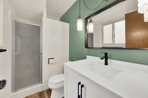 Full bathroom with a shower stall, vanity, and light wood-style floors