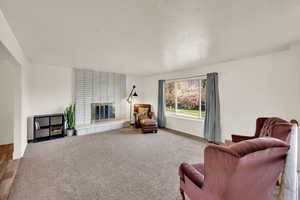Sitting room with a brick fireplace and carpet flooring