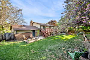 Back of house with brick siding, a fire pit, a chimney, and a deck