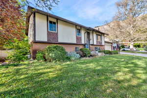 Raised ranch with brick siding, a front yard, and an attached garage
