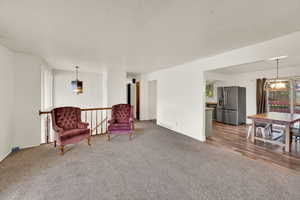 Living area featuring hanging lights and light carpet