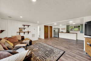 Living room with light wood-type flooring, a textured ceiling, and recessed lighting