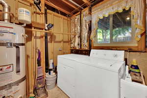 Laundry area with water heater, washing machine and dryer, and concrete floors