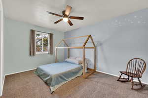 Carpeted bedroom featuring ceiling fan and baseboards