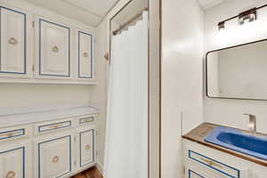 Bathroom with vanity, dark wood-style floors, and a shower with curtain