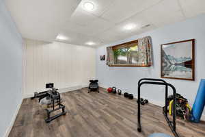Exercise room featuring wood walls, a paneled ceiling, and wood finished floors