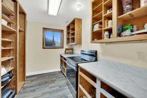 Kitchen featuring stainless steel range with electric cooktop, open shelves, light countertops, and light wood-type flooring